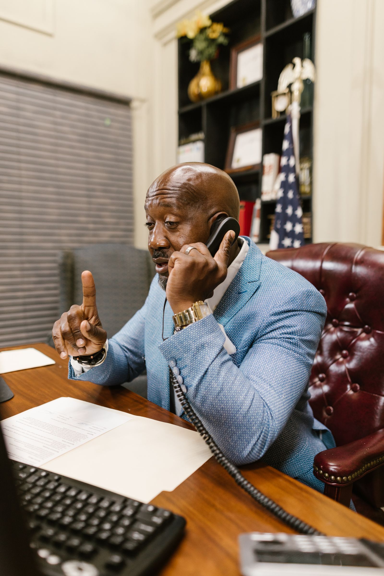 Businessman in a suit making a phone call and taking notes at an office desk